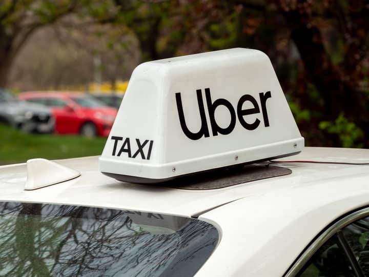 Close-up of a white Uber taxi sign on a car roof in Wrocław, Poland.