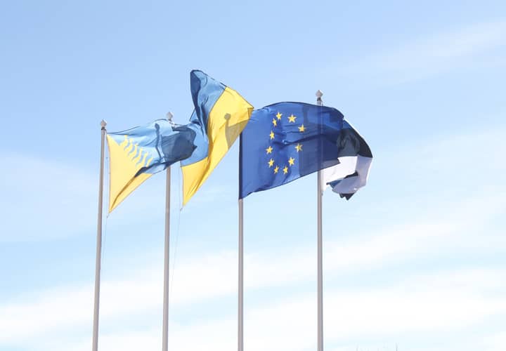 European Union and Estonian flags wave under a clear blue sky, symbolizing unity and harmony.
