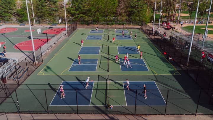 A lively pickleball game at outdoor courts in Philadelphia, captured from above on a sunny day.