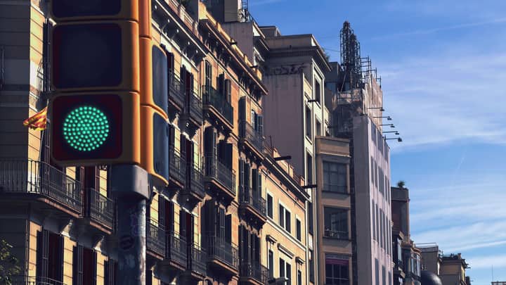 Daytime urban scene in Barcelona with a green traffic light and historic architecture.