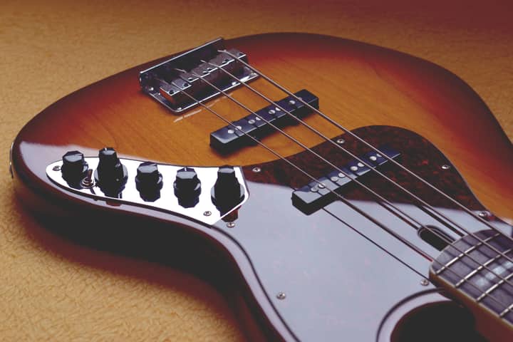 Close-up view of a tobacco sunburst bass guitar showing details of the body, bridge, and knobs.