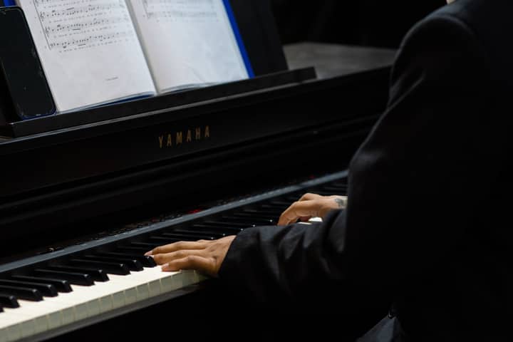 A musician playing a Yamaha piano during a performance, captured in a church setting in Piura, Peru.