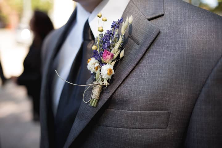 Close-up of an elegant groom wearing a designer suit and floral boutonniere during a wedding ceremony.