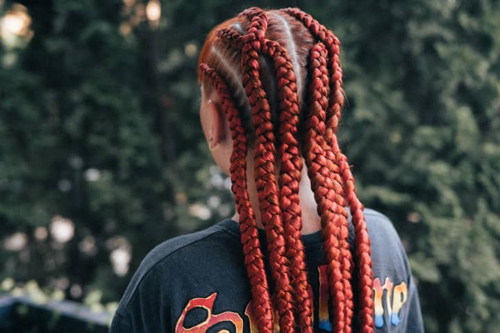 Close-up of vibrant red braids on an adult outdoors.