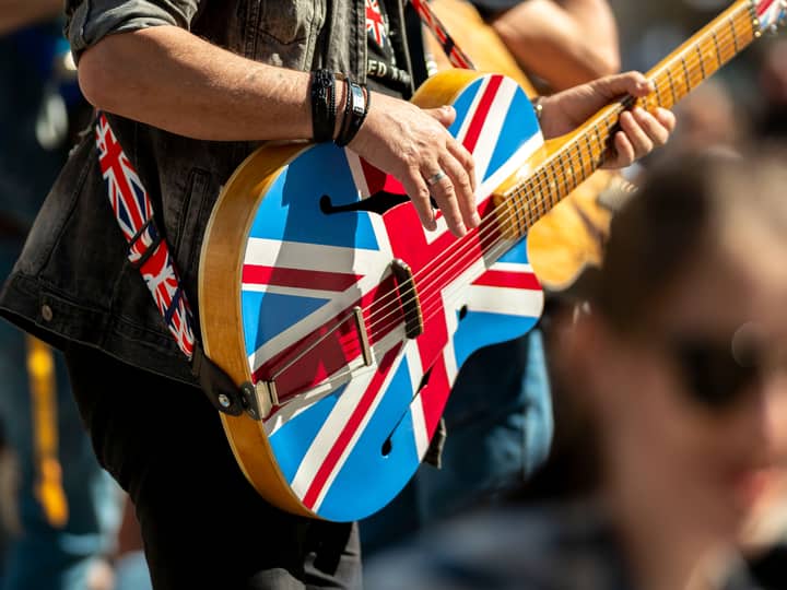 Close-up of a musician playing a Union Jack guitar at an outdoor event in Wrocław, Poland.
