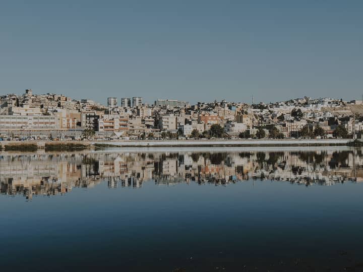 A picturesque cityscape reflecting on the calm water, showcasing urban architecture.