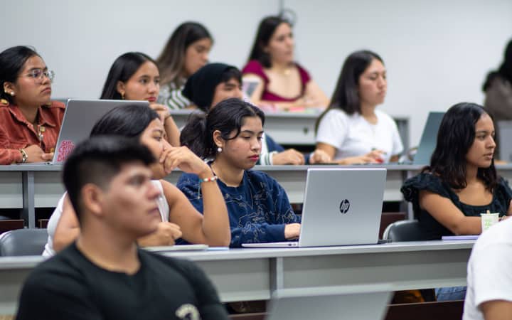 A diverse group of students attentively listens during a university lecture in Piura, Peru.