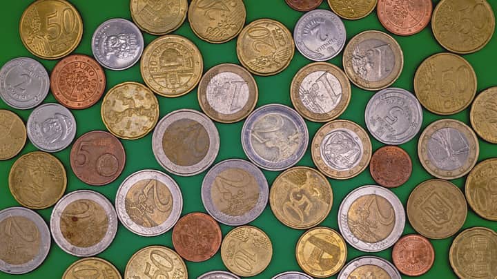 Assorted Euro coins spread on a vibrant green surface, showcasing different denominations and designs.