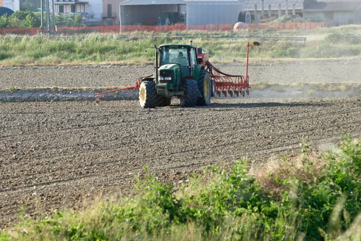 A tractor ploughing a field in Novara, Piedmont, Italy, showcasing rural agriculture.
