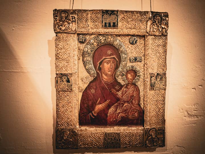 A vintage iconographic painting depicting Madonna and Child in a museum setting under soft lighting.