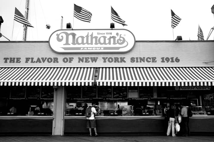 Black and white photo of Nathan's Famous, a New York City icon, with American flags.