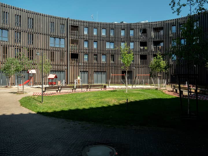 Contemporary apartment complex with green courtyard in Wrocław, Poland, under clear blue skies.