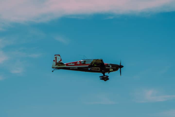 Single-engine aircraft flies high against a bright blue sky, showcasing aviation prowess.