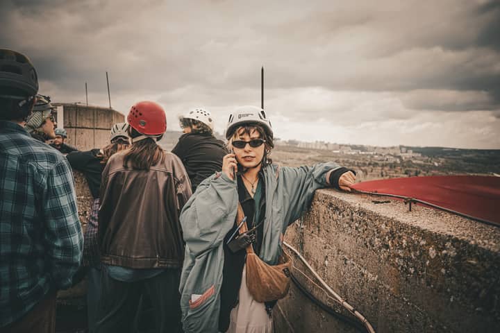 Group of adults on a rooftop tour, wearing helmets, capturing urban exploration adventure.