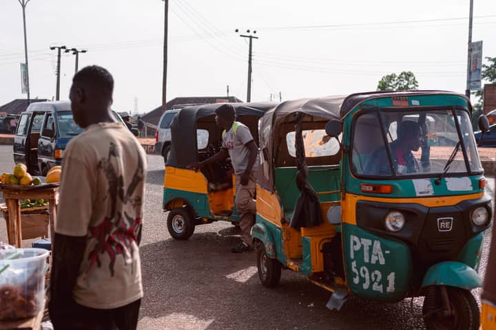 Colorful market scene featuring auto rickshaws and vendors at a bustling street in Jos, Nigeria.