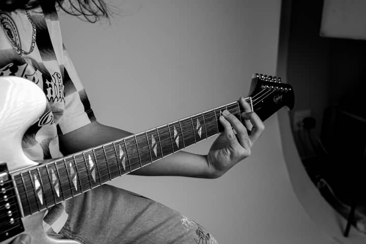 Monochrome image of a person playing an electric guitar, capturing the essence of music creation.