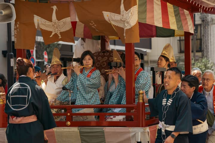 Musicians play flutes during a colorful traditional festival parade in Tokyo, Japan.