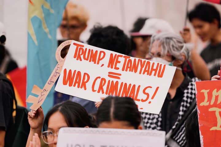 Protesters hold signs at a rally, expressing political views and dissent.