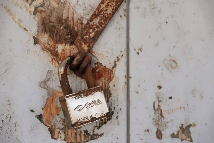 Detailed shot of a rusty padlock on a weathered door conveying security and time passage.