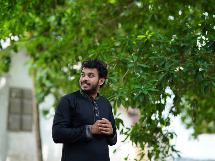 A man in traditional attire enjoys nature in Dhaka, Bangladesh.