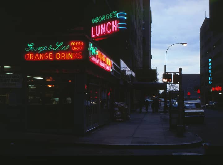 Retro neon signs illuminate a city street in New York, capturing the essence of 1980s urban nightlife.