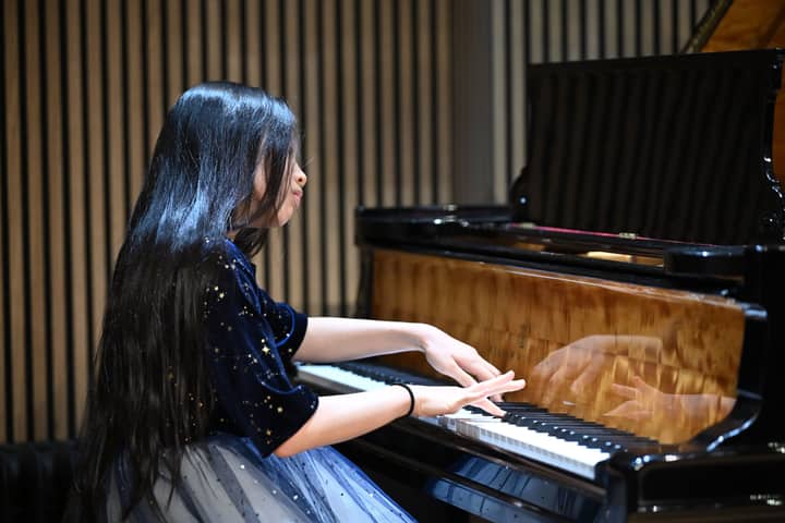 A young woman playing piano indoors, captured in a creative musical expression scene.