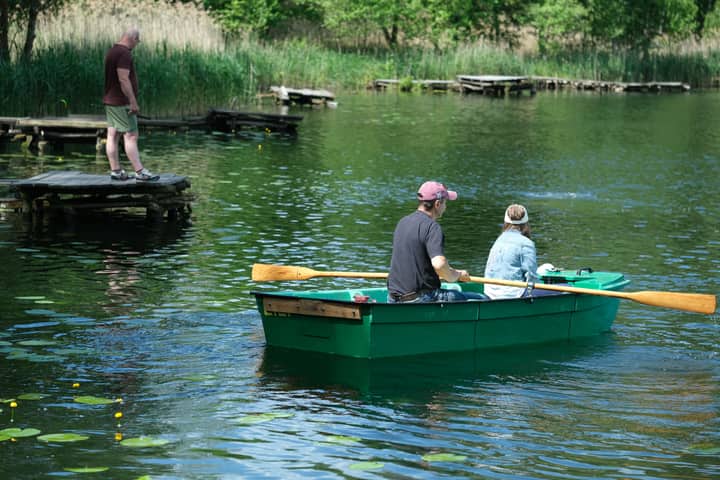 Two people row a boat on a serene lake near a dock. Perfect for leisure and adventure themes.