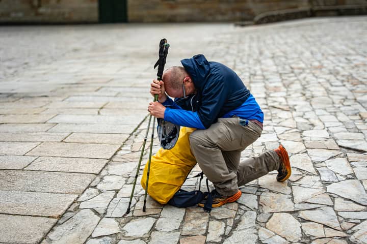 A traveler rests on cobblestones, symbolizing a pilgrimage's completion.