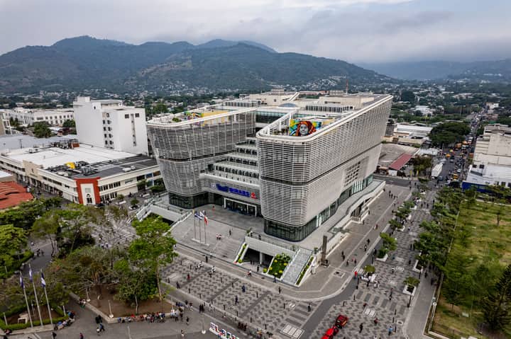Aerial view of San Salvador's modern library and surrounding plaza with mountain backdrop.