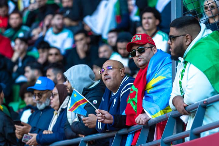 A lively crowd of multi-cultural fans supports their team at a football stadium.