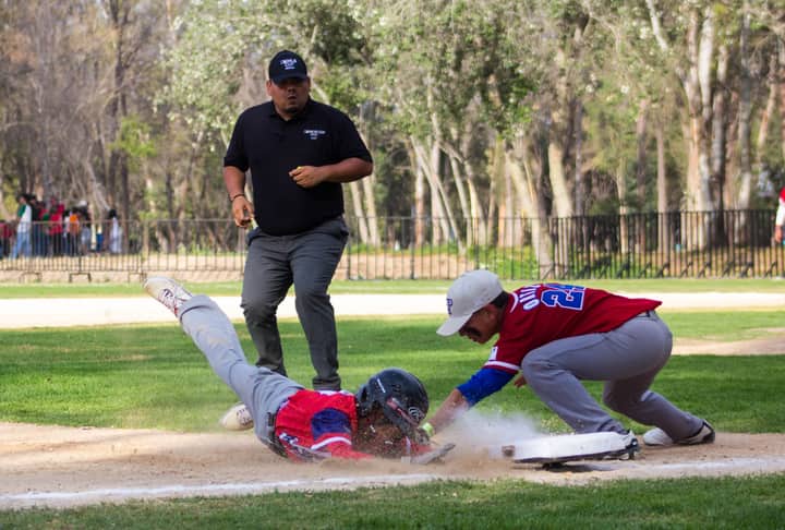 Dynamic action image of a baseball player sliding to base during a game in San Luis Potosí, México.