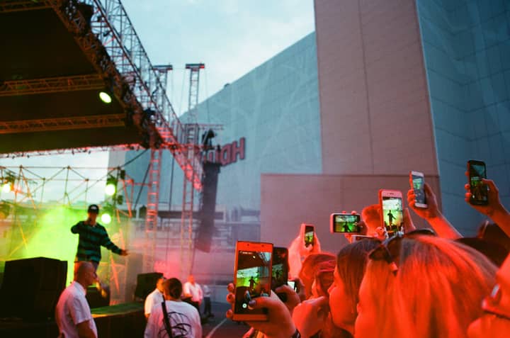 Vibrant live performance captured at a concert with fans recording on smartphones.