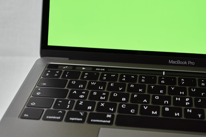 Russian keyboard MacBook Pro with a green screen. Modern electronic device.