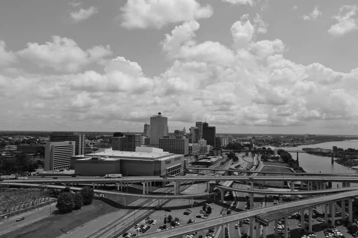 Black and white aerial view of Memphis skyline with prominent roads and clouds in the background.