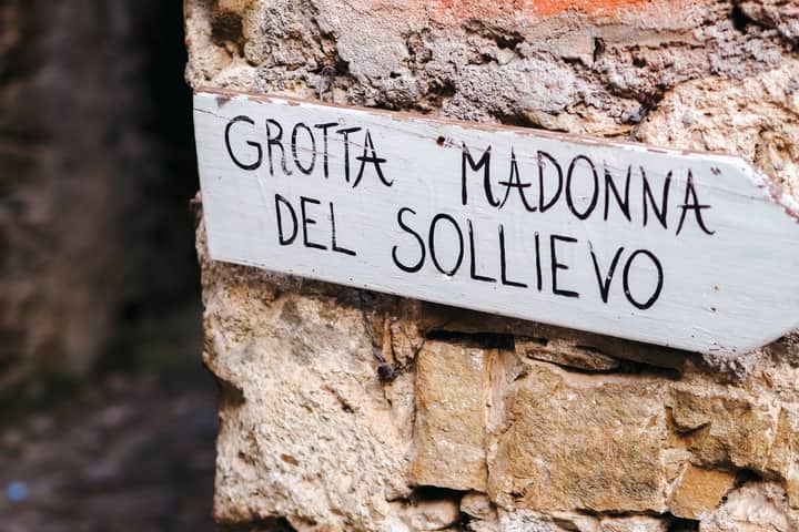 A rustic sign on a stone wall at Grotta Madonna del Sollievo in Provence-Alpes-Côte d'Azur.