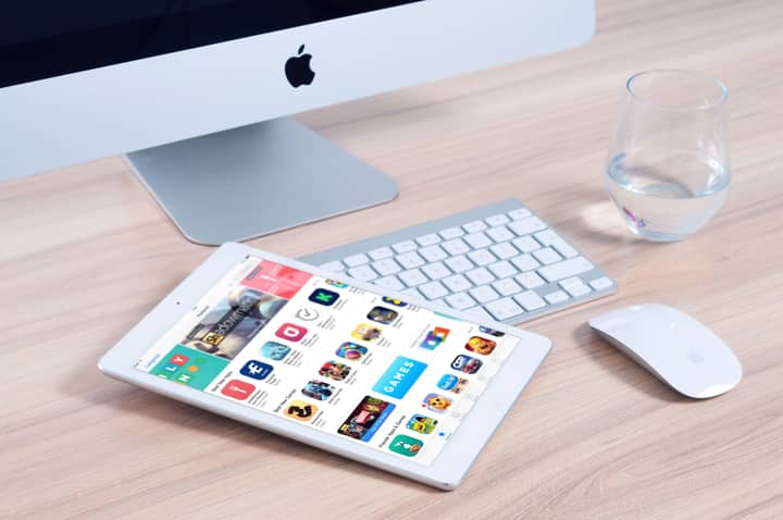 Sleek home office setup featuring an iMac and iPad showcasing apps.