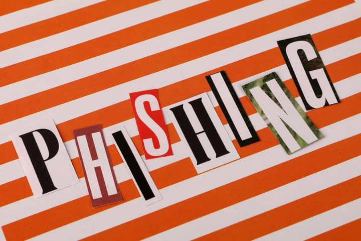 Phishing headline with cut-out letters on an orange striped background illustrating cybersecurity threats.