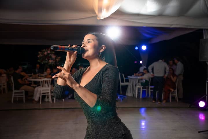 A singer performing energetically at an indoor event in Santo Domingo de los Tsáchilas, Ecuador.