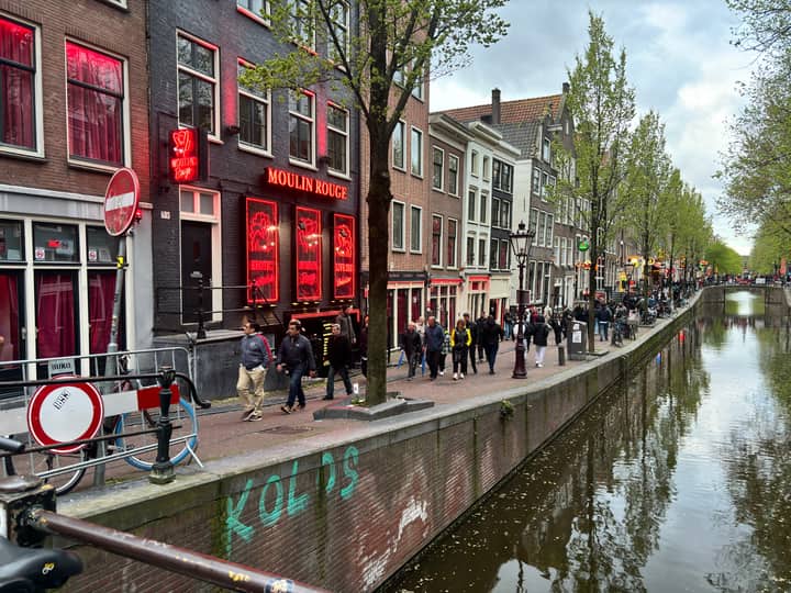Bustling street scene in Amsterdam's Red Light District with iconic Moulin Rouge.