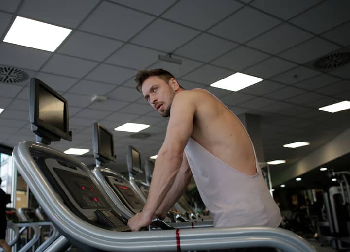 A focused man exercising on a treadmill in a modern gym setting, showcasing dedication and fitness.