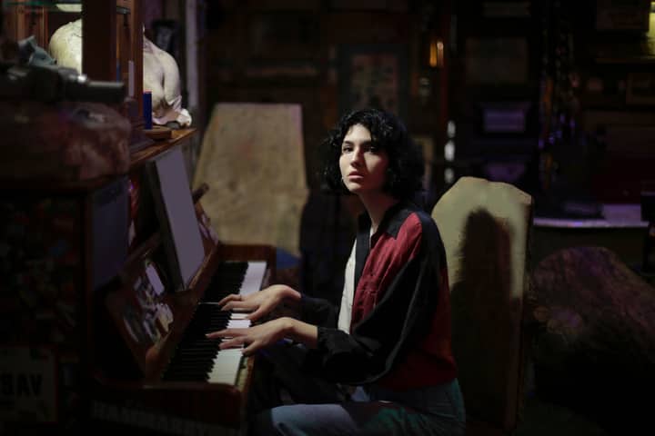 Woman playing the piano in a dark, atmospheric room setting. Moody and artistic vibe.