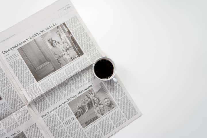 A fresh cup of coffee resting on a newspaper, perfect morning routine setup.