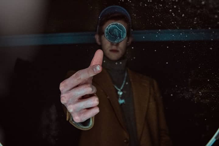 A person dramatically flipping a coin in a dimly lit environment, capturing motion and focus.