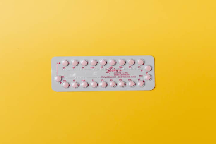 Close-up of a blister pack of pink pills on a vivid yellow background for medication concept.