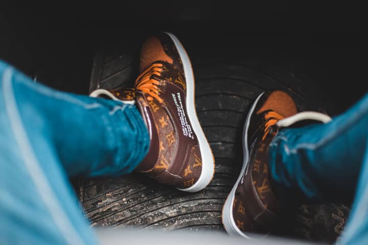 Close-up of luxury branded sneakers with a Louis Vuitton design worn outdoors.