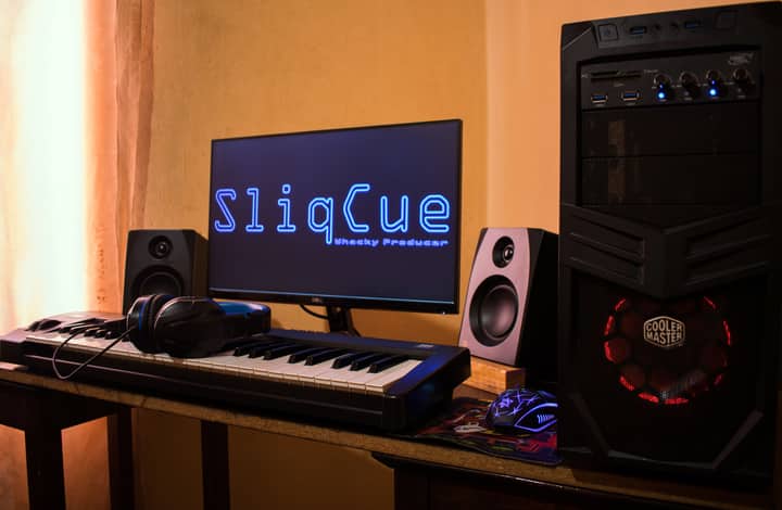 Modern home studio setup with music production equipment including keyboard, computer, and speakers.