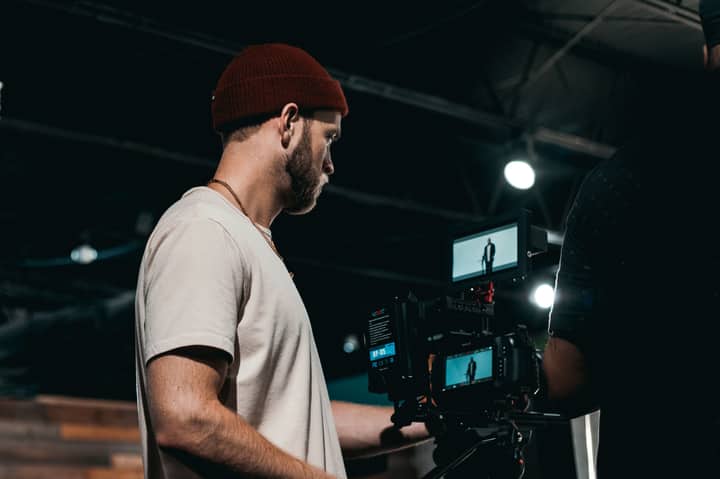 A professional videographer operates a camera indoors, capturing creative content in a studio environment.