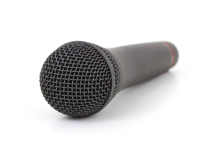 Close-up of a black microphone on a white background, ideal for audio equipment themes.