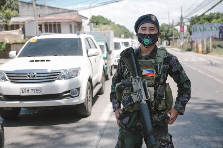 A Philippine soldier in uniform and mask standing on a city street, showcasing military presence.