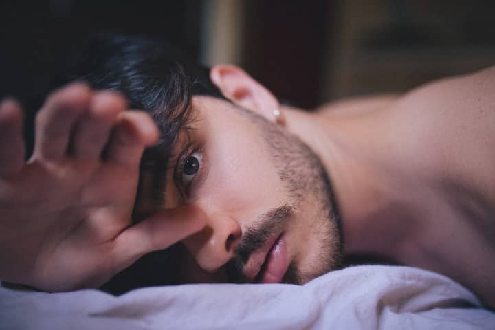 Intimate close-up of a bearded man lying on fabric, capturing a serene moment indoors.